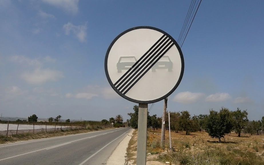 The circular red-bordered no-overtaking traffic sign showing two cars
