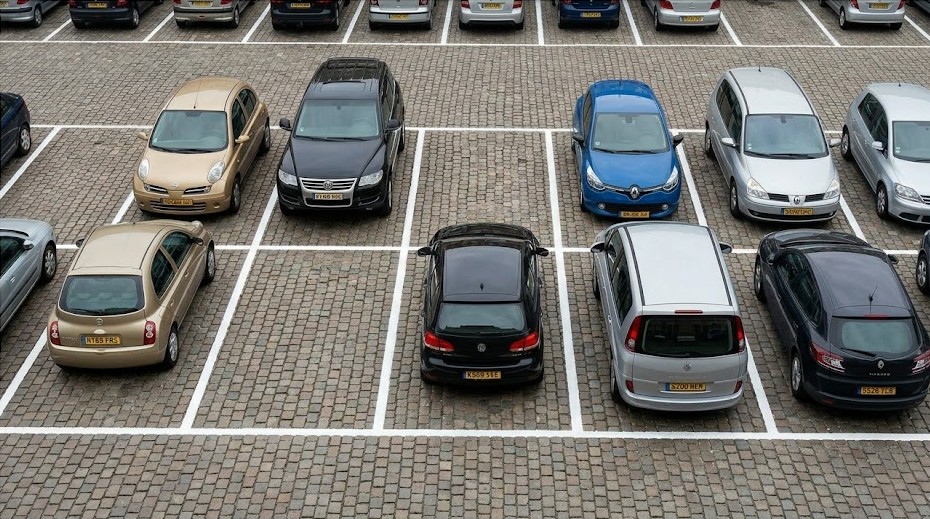 A car parked within a marked parking bay, with a no-parking sign for contrast