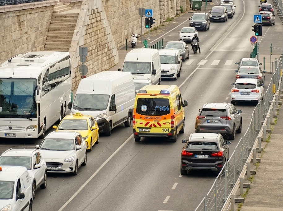 Top-down street view showing cars pulling to the right and stopping to create a clear lane for an ambulance passing through traffic