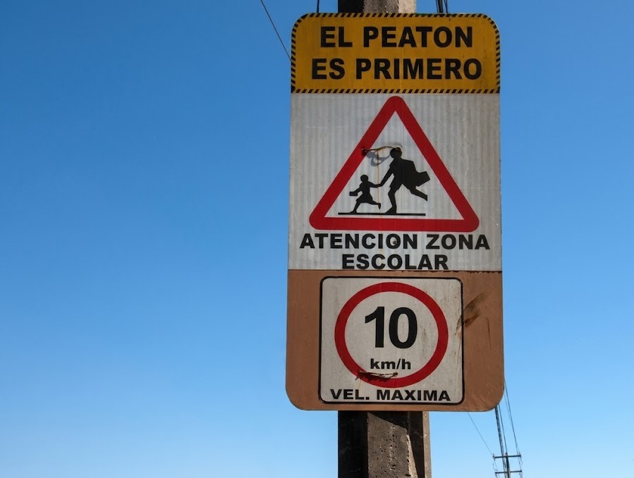 A school-zone sign with children nearby