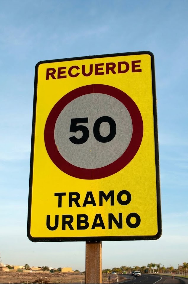 An urban street with a 30 km/h sign and pedestrians nearby