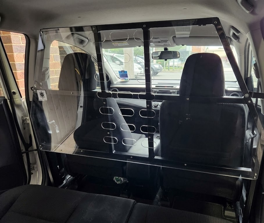 Side-view cross-section of a van or estate car showing a rigid partition or protection net between the cargo area and the passenger cabin