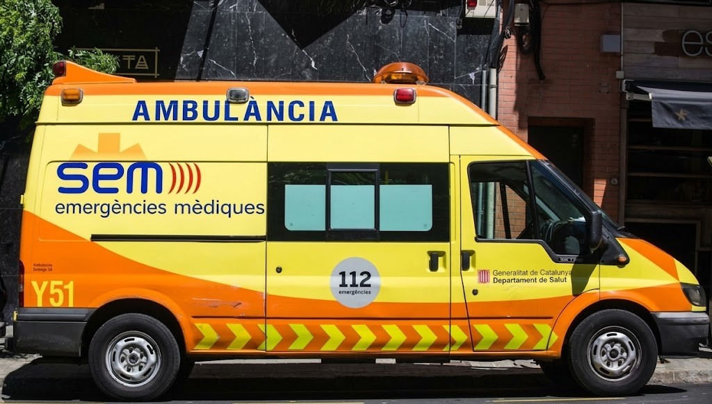 An ambulance with siren and flashing lights as surrounding traffic pulls aside
