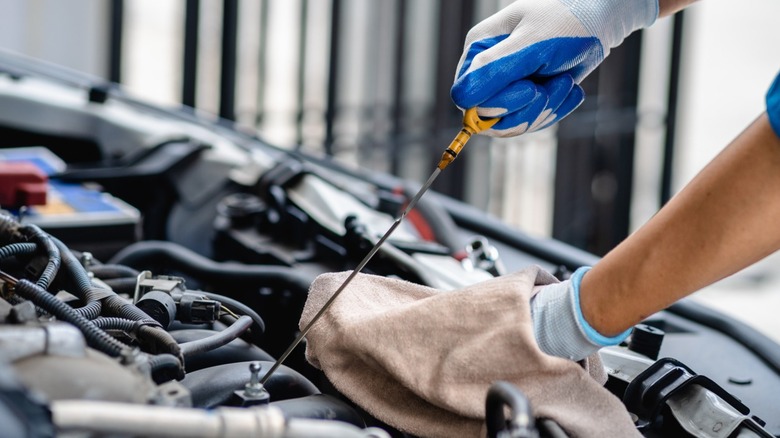 Question image: How should the engine oil level be checked with the dipstick?