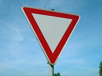 Question image: What shape and colour are the signs that warn of a hazard on the road?